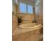 Relaxing bathroom showcasing a soaking tub with tiled surround and a bright shuttered window at 2622 Clarinet Dr, Orlando, FL 32837