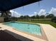 Backyard pool with lush green grass, surrounded by a black metal fence, and under a blue awning at 2622 Clarinet Dr, Orlando, FL 32837