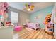 Bright bedroom featuring a ceiling fan, wood floors, and a plush pink ottoman at 3142 Dark Sky Dr, Harmony, FL 34773