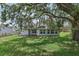Expansive backyard features a covered patio, green lawn, and mature trees for outdoor enjoyment at 3326 Sassaquin Ct, Orlando, FL 32818