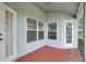 Covered patio area showcasing a durable red floor and multiple doors and windows at 3326 Sassaquin Ct, Orlando, FL 32818