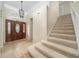 Bright foyer featuring elegant tile flooring, a decorative front door, and carpeted stairs leading to the second floor at 3585 Ventura Club Cir, Orlando, FL 32822