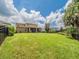 Expansive backyard with lush green grass, mature trees, and a screened lanai at 461 Brunswick Dr, Davenport, FL 33837