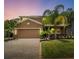 Charming two-story home features a well-manicured lawn, tropical landscaping, and a brick paver driveway at 461 Brunswick Dr, Davenport, FL 33837