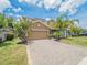 Two-story home with a well-manicured lawn, mature landscaping, and a brick paver driveway at 461 Brunswick Dr, Davenport, FL 33837