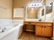 Bathroom with large mirror, wood cabinets, and a garden tub with tile surround at 500 Wellesly St, Oviedo, FL 32765