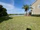 Backyard view of the lake, lush lawn, mature trees, and building at 506 Terrace Spring Dr, Orlando, FL 32828