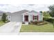 Charming single-story home with well-manicured lawn, gray siding, and a pop of color from the red front door and shutter at 561 Andrea S Cir, Haines City, FL 33844