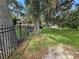 Iron fence with manicured green lawn and beautiful trees, with waterfront homes in the background at 606 Butler St, Windermere, FL 34786