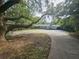 Ranch-style home with a large driveway, mature trees, and a carport, blending classic charm with outdoor living at 606 Butler St, Windermere, FL 34786