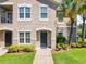 Inviting two-story condo featuring a well-manicured lawn, lush shrubbery, and mature palm trees at 6524 Swissco Dr # 1012, Orlando, FL 32822