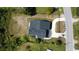 A bird's-eye view displays the home's layout, roof, long driveway, lush greenery, and surrounding neighborhood at 9122 Trevarthon Rd, Orlando, FL 32817