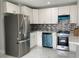 Modern kitchen with stainless steel appliances, white cabinetry, and mosaic backsplash at 9122 Trevarthon Rd, Orlando, FL 32817