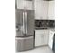 Contemporary kitchen with white cabinets, stainless steel refrigerator, and mosaic backsplash at 9122 Trevarthon Rd, Orlando, FL 32817