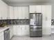 New kitchen features white cabinets, granite countertops, a mosaic backsplash, and stainless steel appliances at 9122 Trevarthon Rd, Orlando, FL 32817