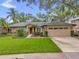Charming single-story home with lush landscaping, well-manicured lawn, and a two-car garage at 9275 Lake Sharp Ct, Orlando, FL 32817