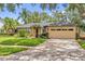 Inviting single-story house with a neat lawn, mature trees, and a two-car garage at 9275 Lake Sharp Ct, Orlando, FL 32817