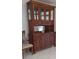 Close-up of a wooden hutch with glass doors and a chair on a tiled floor at 10928 Tangora St, Orlando, FL 32825