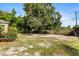 Lush, green backyard featuring grass, mature trees, and fence line under a clear blue sky at 1104 W Marjorie St, Lakeland, FL 33815