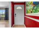 View of front door with red accent wall, sidelight, and artwork at 1104 W Marjorie St, Lakeland, FL 33815