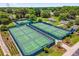 Aerial view of well-maintained tennis and pickleball courts surrounded by lush greenery at 1254 Spartanburg Way, The Villages, FL 32162