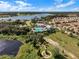 Aerial view of a community pool, clubhouse, and lake near colorful homes in a sunny neighborhood at 1378 Roxy Ln, Winter Garden, FL 34787