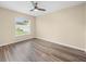 Bedroom with wood floors, ceiling fan, and large window with blinds overlooking the lawn at 14322 Pine Cone Trl, Clermont, FL 34711
