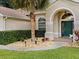 Inviting home entrance with a manicured lawn, stone landscape features, and a vibrant green front door at 14322 Pine Cone Trl, Clermont, FL 34711