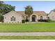Charming single-story home boasts a lush lawn, manicured landscaping, and a welcoming entrance with a stately palm tree at 14322 Pine Cone Trl, Clermont, FL 34711