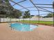 A screened pool surrounded by concrete, landscaping, and a white fence offers a private backyard oasis at 14322 Pine Cone Trl, Clermont, FL 34711