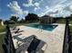 Community pool with lounge chairs surrounded by a black fence on a partly cloudy day at 1470 Daniels Cove Dr, Winter Garden, FL 34787