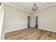 Neutral bedroom featuring modern light fixture, wood-look flooring, and open doors to other rooms at 1660 Justin Matthew Way, St Cloud, FL 34771