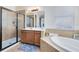 Bathroom with walk-in shower, soaking tub, wood cabinets, and neutral tile at 2071 Remembrance Ave, St Cloud, FL 34769