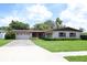 Charming single-story home with a manicured lawn, mature trees, and a driveway leading to an attached garage at 2417 Bayfront Pkwy, Orlando, FL 32806