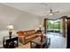 Living room with a leather couch, wood-look tile flooring, and a sliding glass door to the screened patio at 3210 Sonesta Ct # B, Clermont, FL 34711