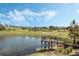 Picturesque pond view with wooden dock surrounded by lush landscaping under a blue sky at 3210 Sonesta Ct # B, Clermont, FL 34711