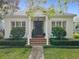 Charming home with a brick staircase leading to a dark wood front door framed by stately columns and lush landscaping at 4545 Fox St, Orlando, FL 32814