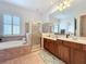 Primary bathroom featuring a double sink vanity, shower and soaking tub with shutters for privacy at 4545 Fox St, Orlando, FL 32814
