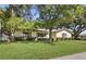 Single-story home with lush green lawn and mature trees, offering shade and curb appeal at 5334 Cypress Dr, Winter Park, FL 32792