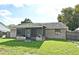 View of the backyard with a screened-in porch, grassy lawn and wooden fence on a sunny day at 5588 Garden Grove Cir, Winter Park, FL 32792
