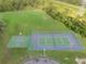 Overhead view of the tennis and basketball courts, highlighted by green fields and surrounded by green trees at 10675 Fairhaven Way, Orlando, FL 32825