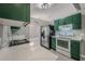 This kitchen features stainless steel appliances, stylish green cabinets, and sleek white countertops at 10675 Fairhaven Way, Orlando, FL 32825