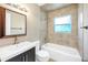 The bathroom features a tub with tiled wall, vanity and decorative window that provides natural light and privacy at 1204 Marie Ave, Apopka, FL 32703