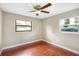 Inviting bedroom with dual windows offering natural light, fan, and wood-look floors, perfect for rest and relaxation at 1204 Marie Ave, Apopka, FL 32703