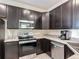 Well-equipped kitchen with dark cabinetry, stainless steel appliances, and modern countertops, ideal for cooking at 129 Boydfield Ln, Davenport, FL 33837
