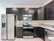 Modern kitchen featuring stainless steel appliances, dark cabinets, and a functional layout for easy meal preparation at 129 Boydfield Ln, Davenport, FL 33837