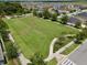 Expansive green common area and community with tree lined sidewalks near homes in aerial view at 1565 Diamond Loop Dr, Kissimmee, FL 34744