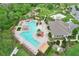 Aerial view of a community pool area with ample seating, a clubhouse, playground, and lush landscaping at 1565 Diamond Loop Dr, Kissimmee, FL 34744