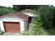 Quaint one-story home with a brown roof, attached garage and mature trees at 1612 Eastern Ave, St Cloud, FL 34771