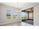 Bright dining area features a modern chandelier, three windows, and a large sliding glass door to an outdoor living space at 1709 Benoit Ter, Davenport, FL 33837